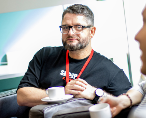 A lecturer sitting in an armchair, facing the camera and looking inspired